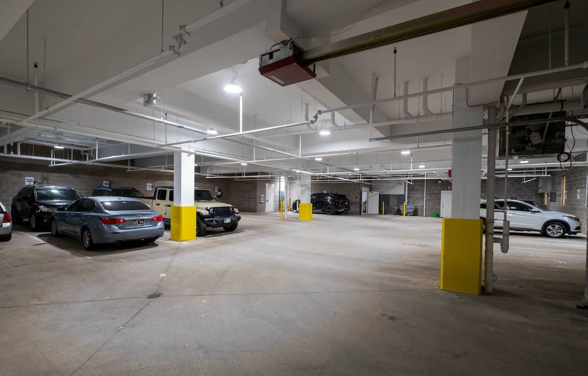 Underground parking lot with multiple parked cars and concrete pillars.