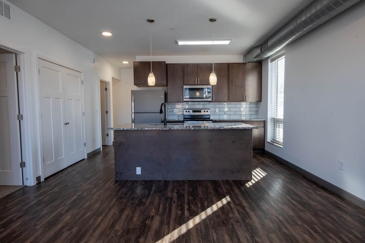 Modern kitchen with dark wood cabinets, stainless steel oven, microwave, and granite countertops.