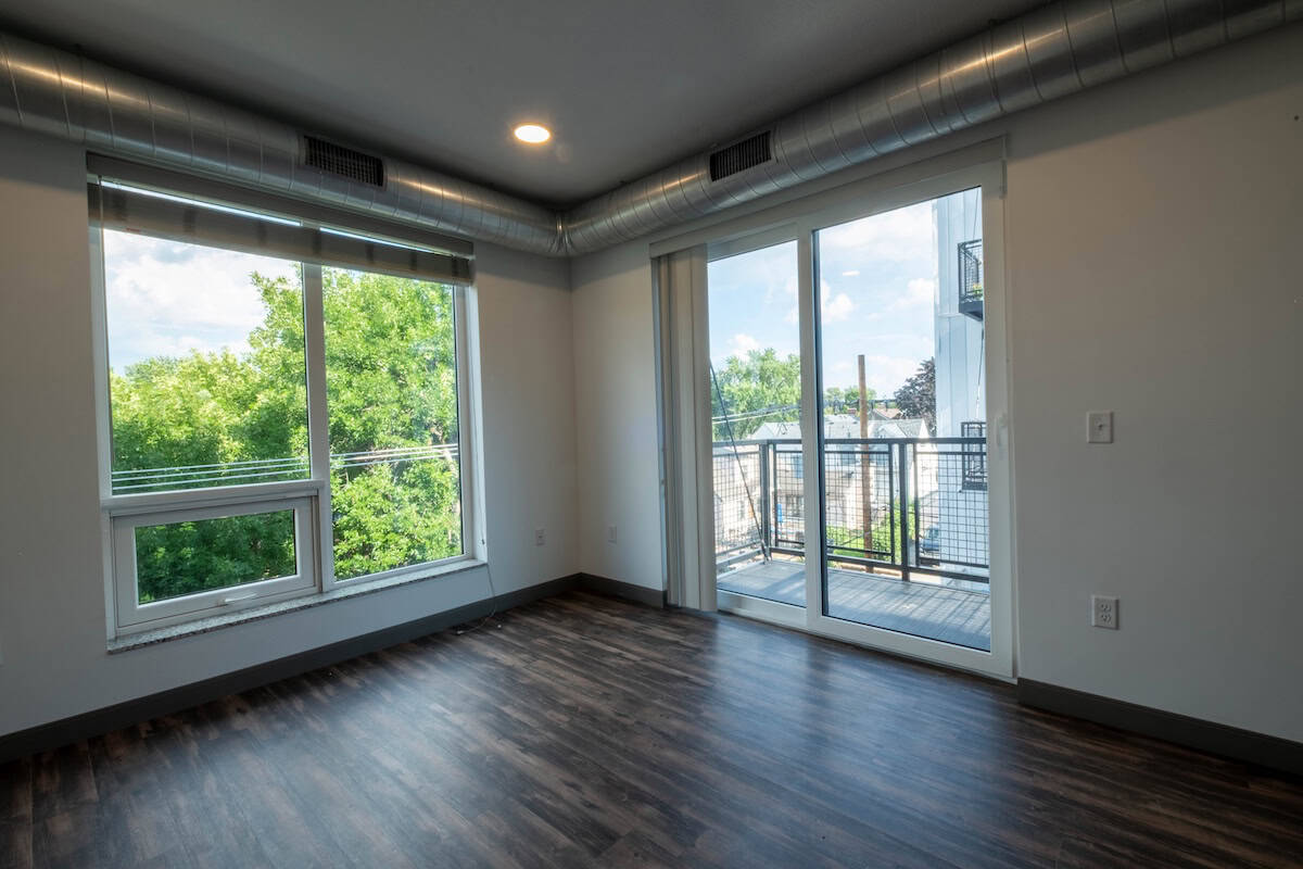 Bright living space with floor-to-ceiling windows and a balcony overlooking greenery.