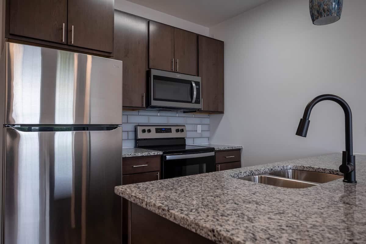 Modern kitchen with stainless steel appliances and granite countertops at The Pearl Apartments, Minn.