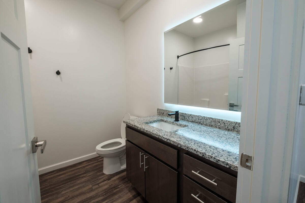 Bathroom with granite vanity, mirror, and toilet in a contemporary apartment.