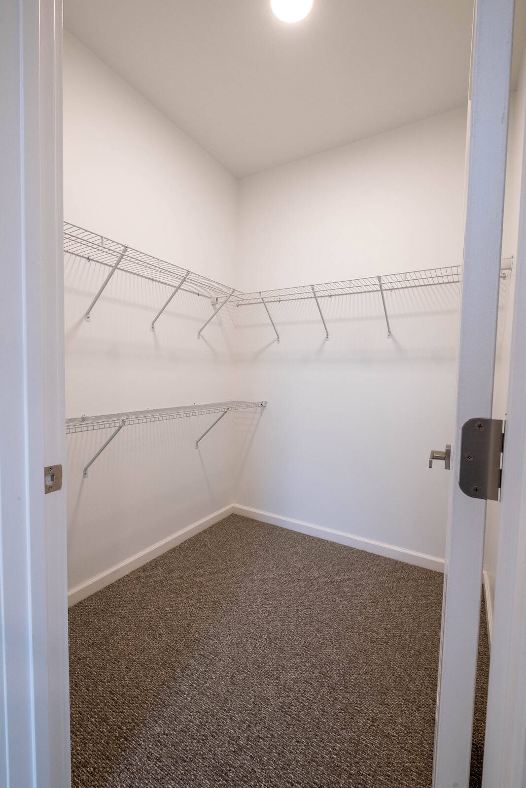 Walk-in closet with white wire shelving in a modern apartment.
