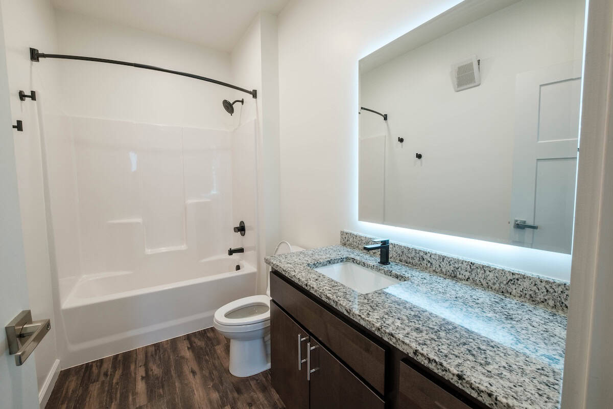 Bright bathroom featuring a bathtub, toilet, and granite vanity at The Pearl Apartments in Minneapol.