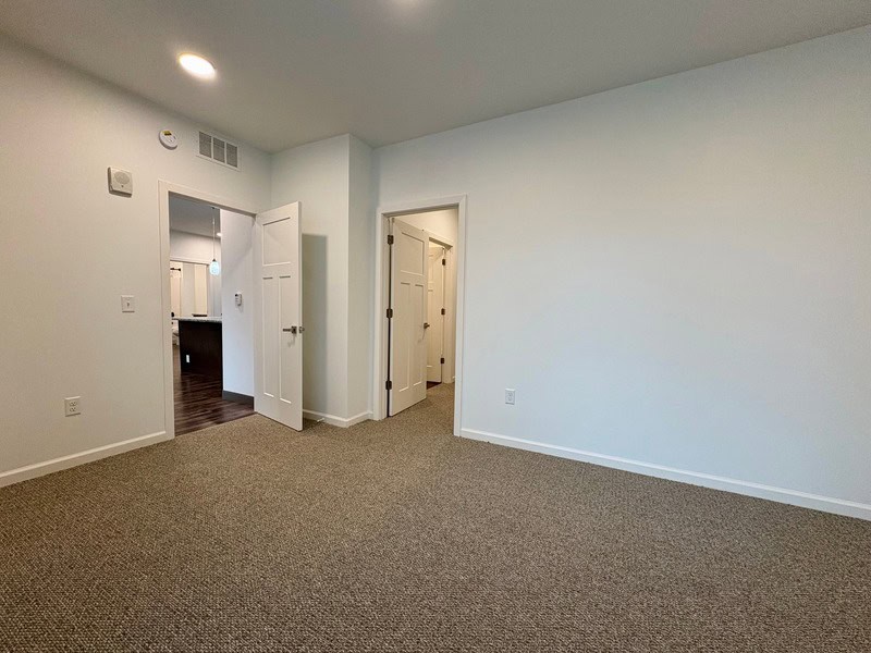Interior view of a clean, spacious apartment with white walls and carpeted floors in Minneapolis, Mi.