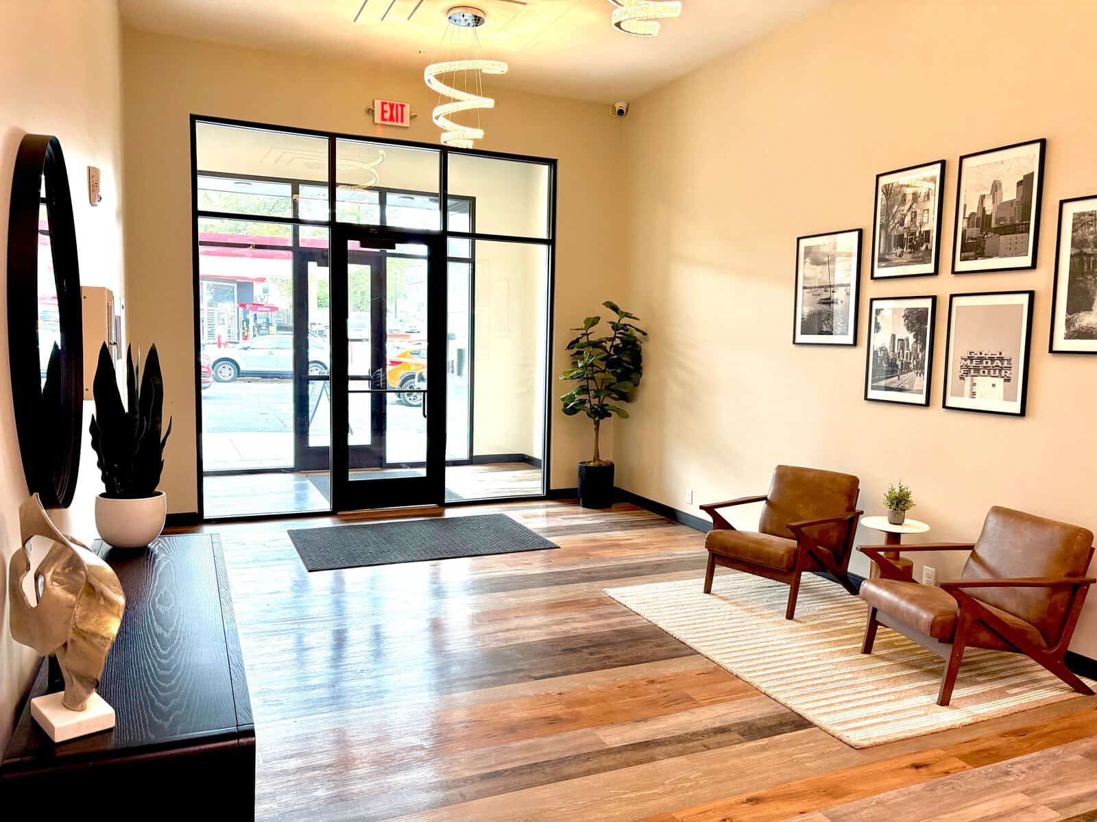 Stylish apartment lobby featuring comfortable chairs, framed cityscape photos, and a welcoming entra.