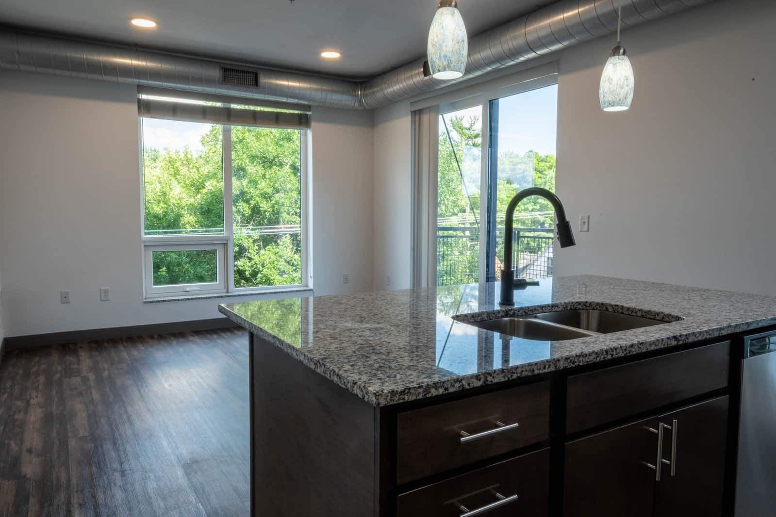 Modern kitchen with large windows and granite countertops in The Pearl Apartments, Minneapolis, MN.