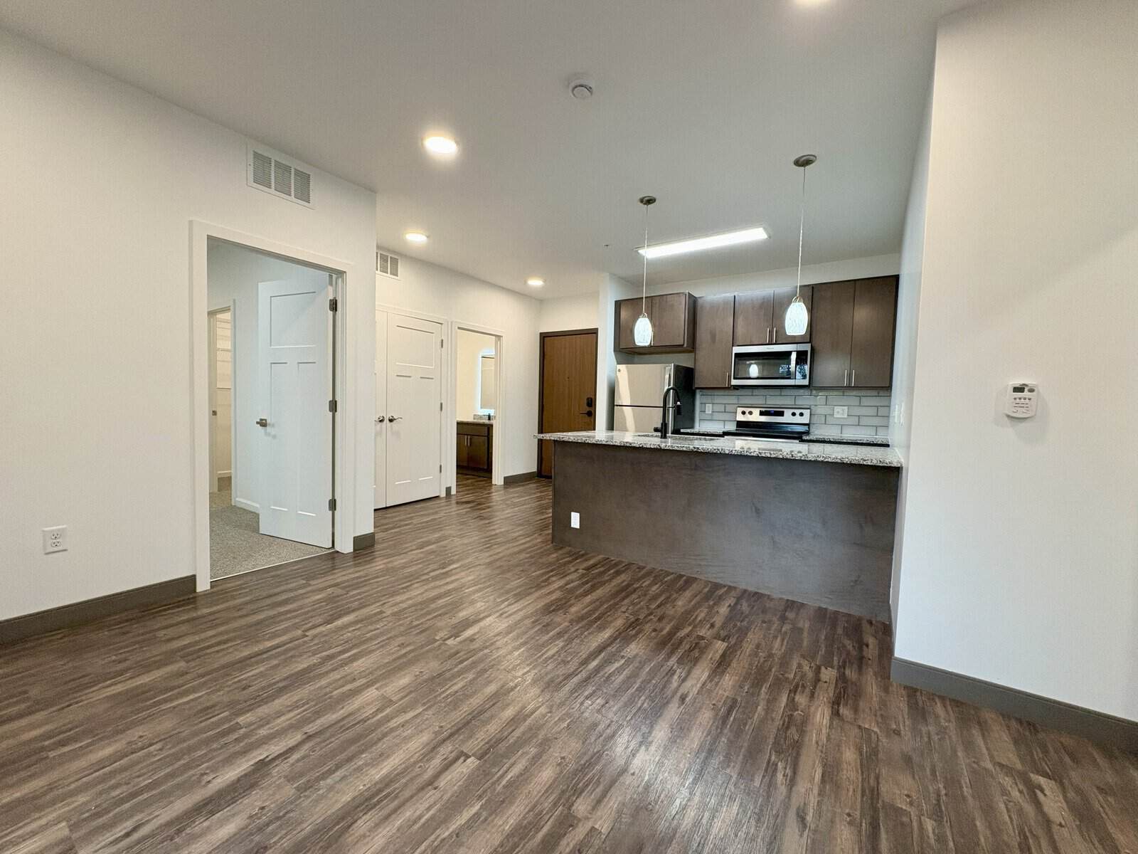 Bright, spacious kitchen with dark wood cabinets and stainless steel appliances in The Pearl Apartme.