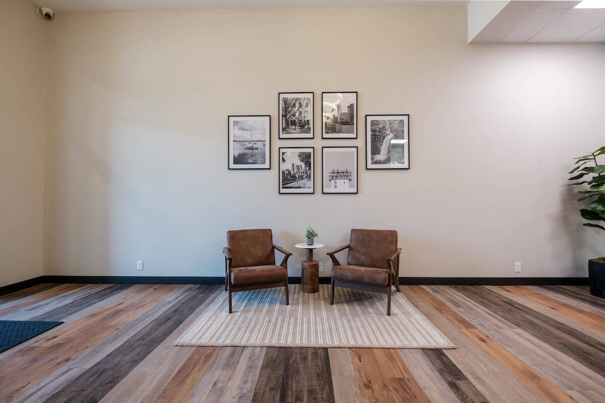 Modern apartment lobby with two brown chairs and framed black-and-white artwork on the wall.